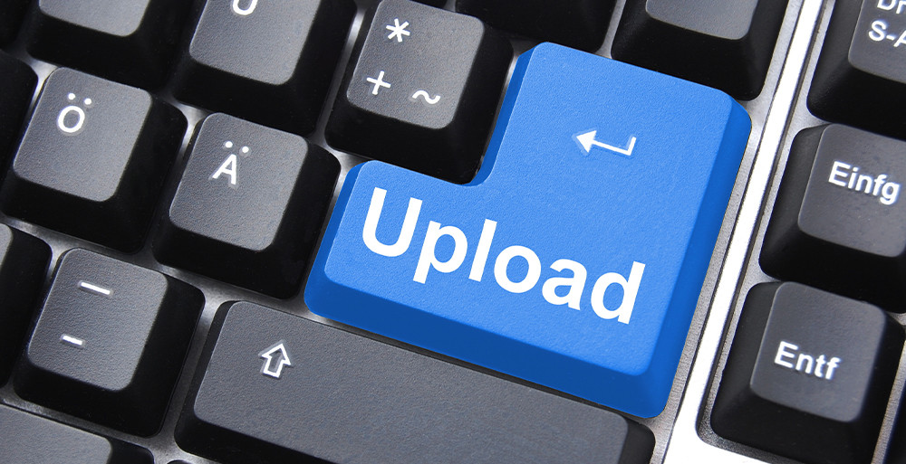 Nahrávanie súborov jedným klikom Prst stláča modré tlačidlo „Upload“ s ikonou cloudu