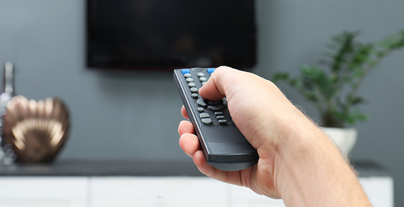  Muž prepína na ovládači televízne kanály.